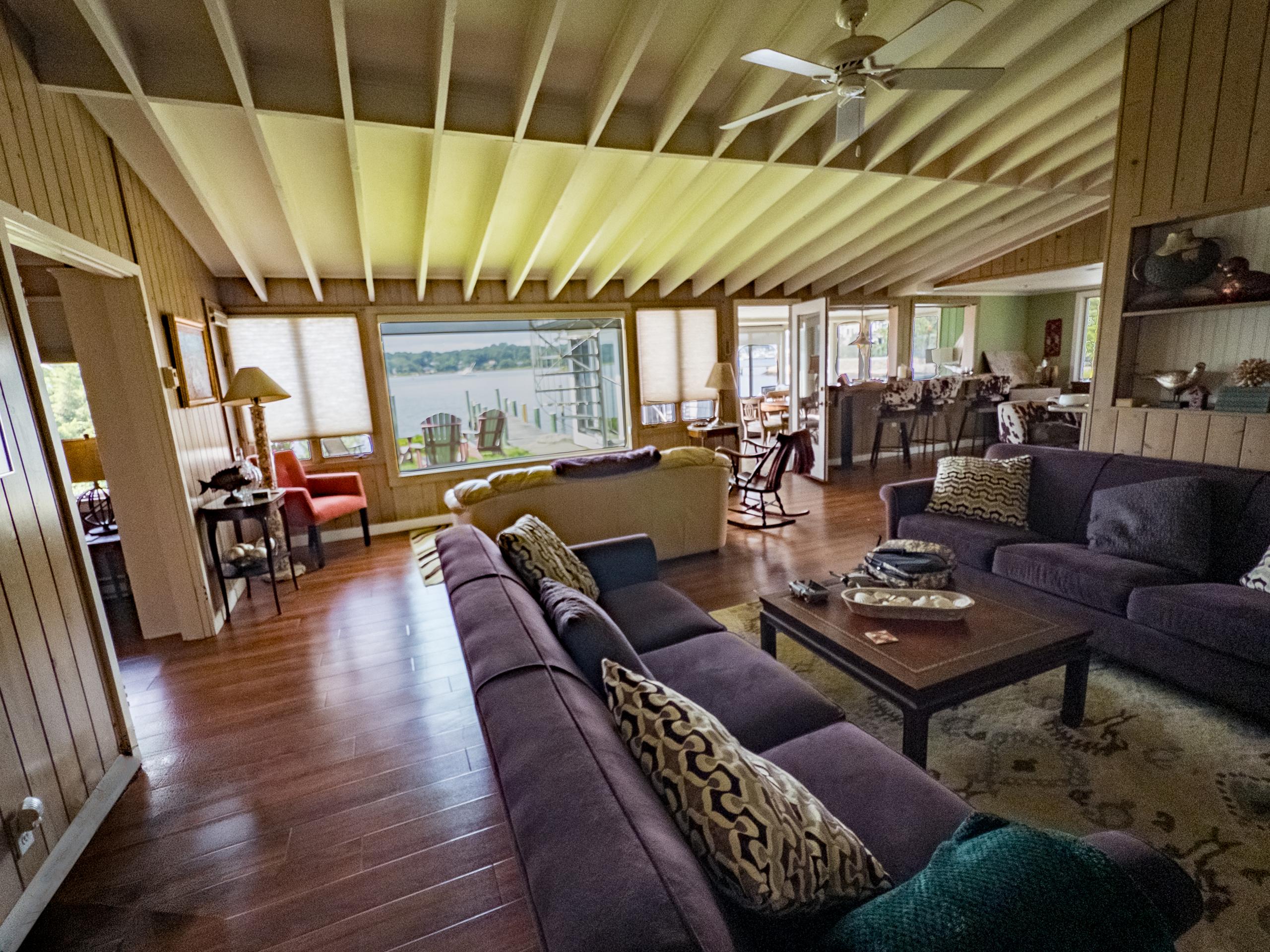 The living room: sectionals facing the picture window, with the dock and Adirondack chairs on the point just outside.