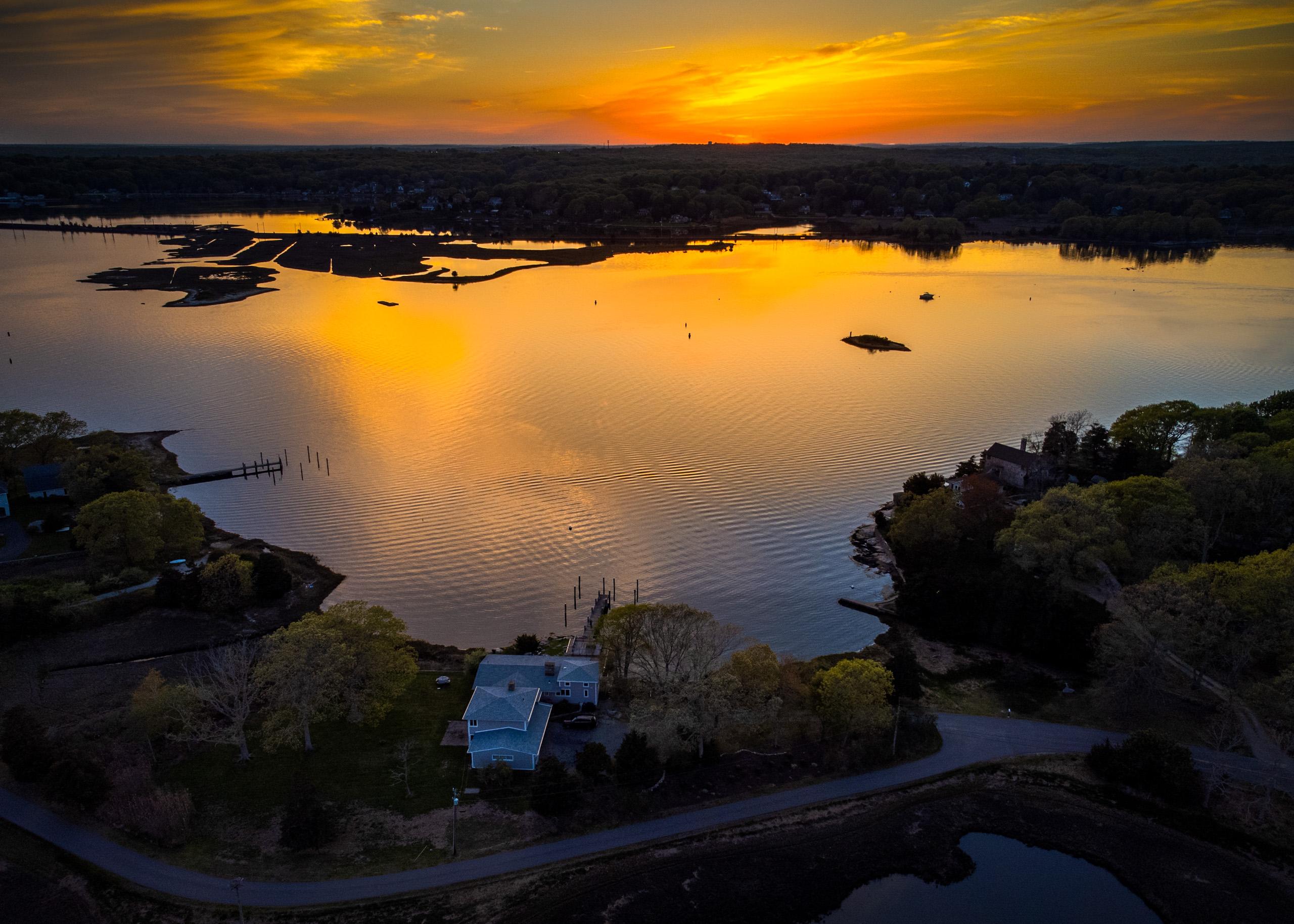Sunset over the Mystic River, with the house at the water's edge.