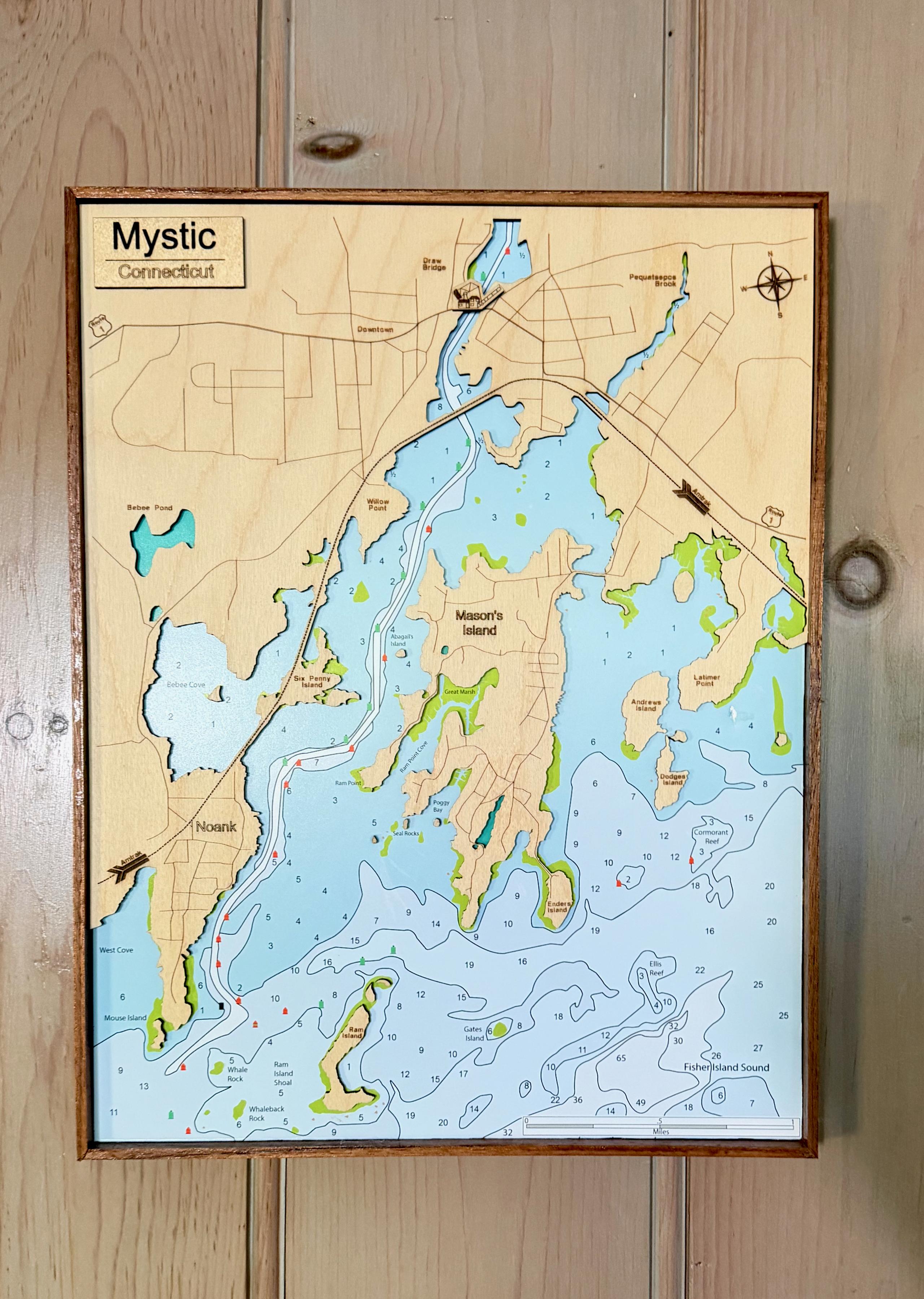 A layered wood map of Mystic and Mason's Island, with water depths marked, hanging on a pine wall