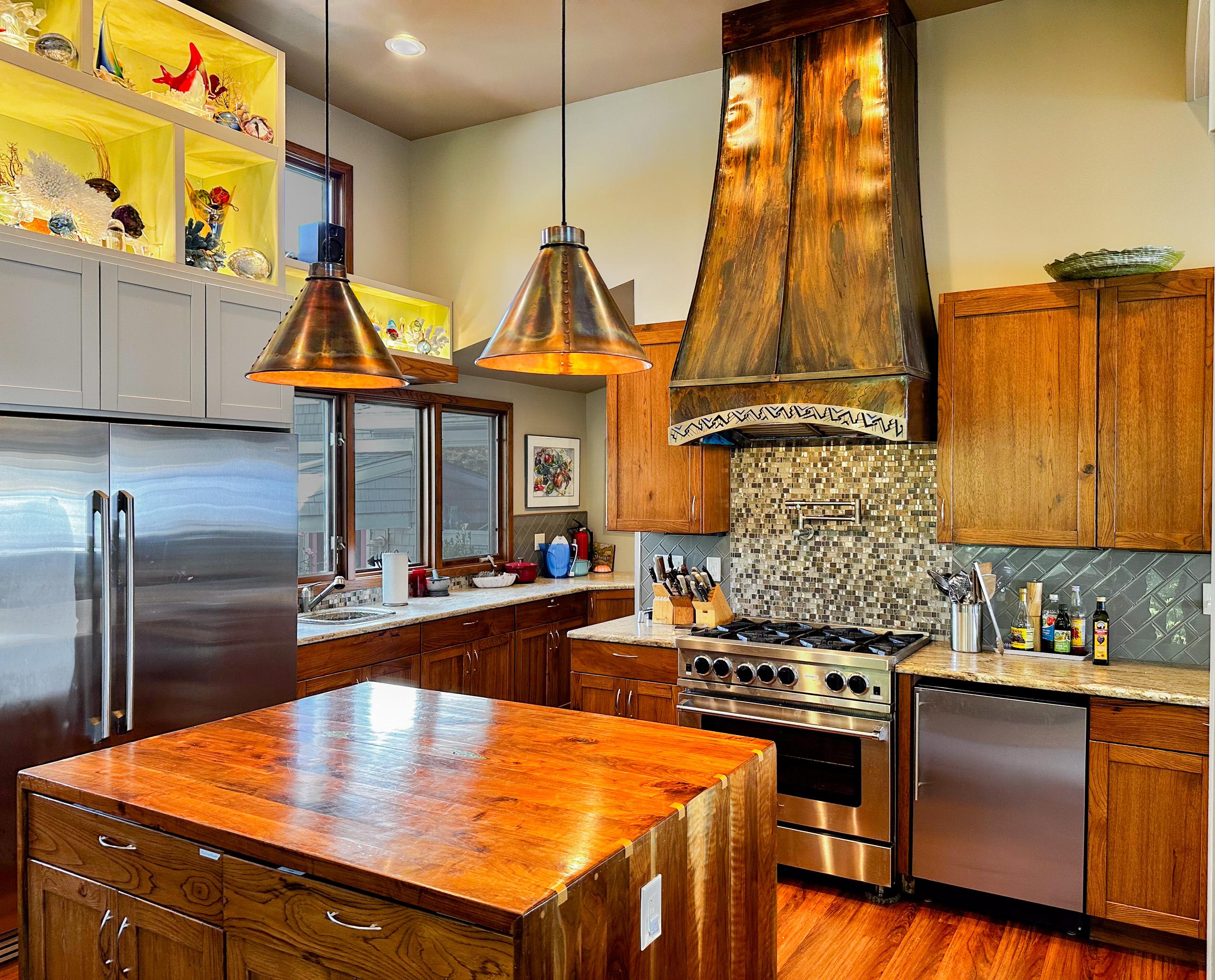 The kitchen under its twelve-foot ceilings: BlueStar range, walnut island, and the copper hood.