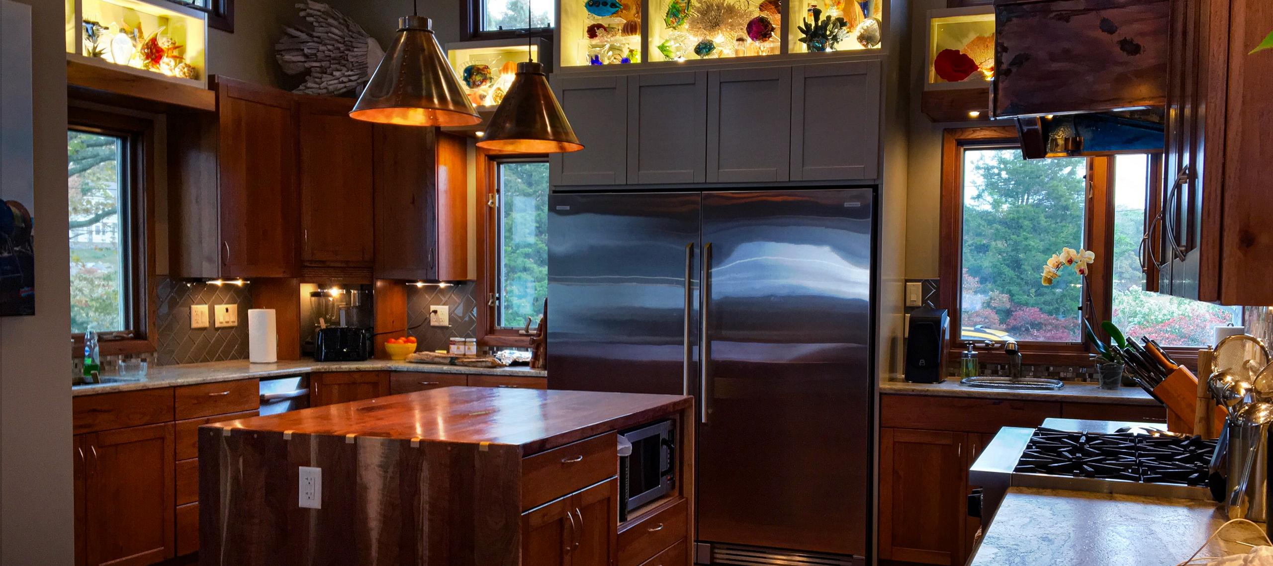 The kitchen at 26 Schoolhouse: BlueStar range, walnut island, and the hand-built copper hood under twelve-foot ceilings