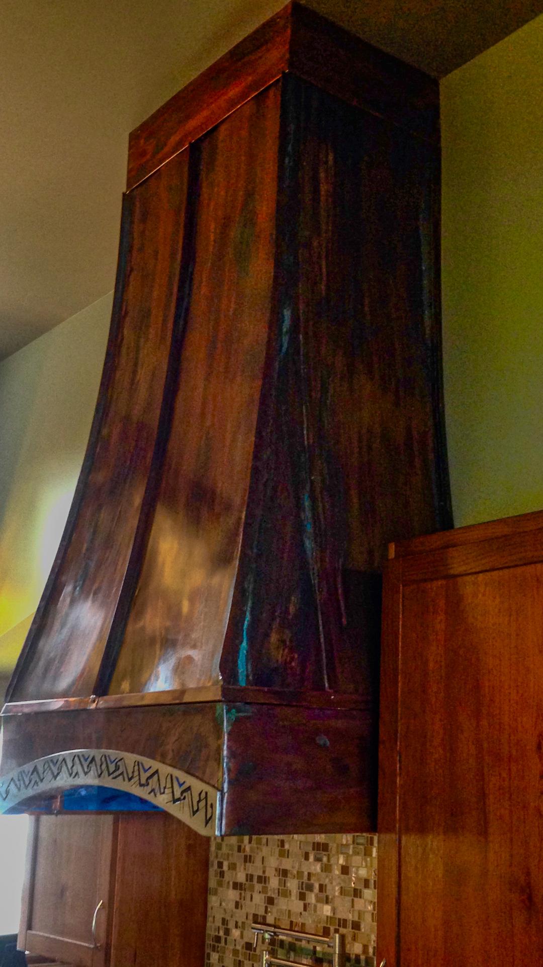 The hood up close: waterjet-cut, TIG-welded, copper skin chemically patinated, with the pewter arch across the front.