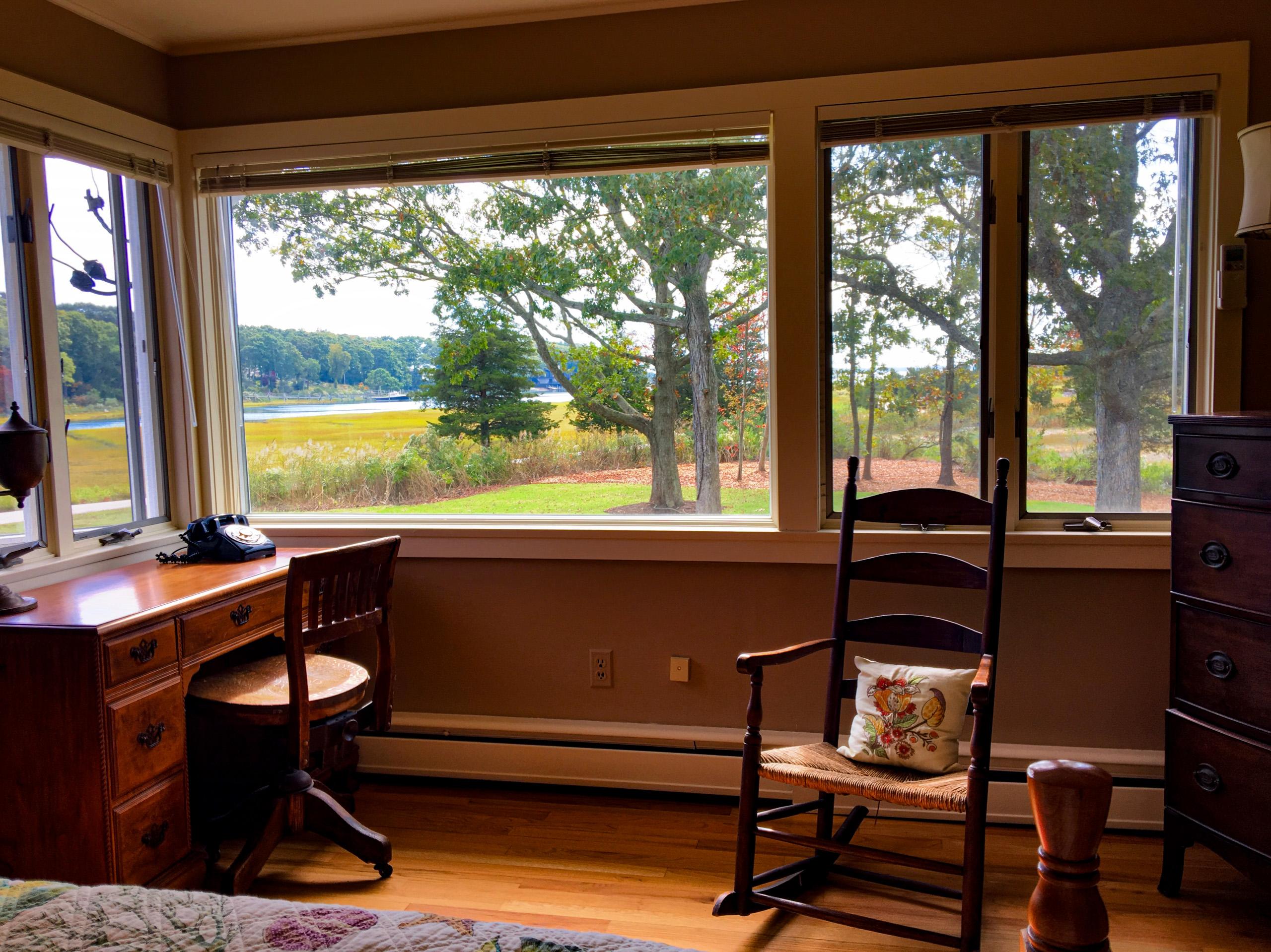 The crow's nest corner windows: the writing desk and rocking chair looking down the lawn to the estuary.