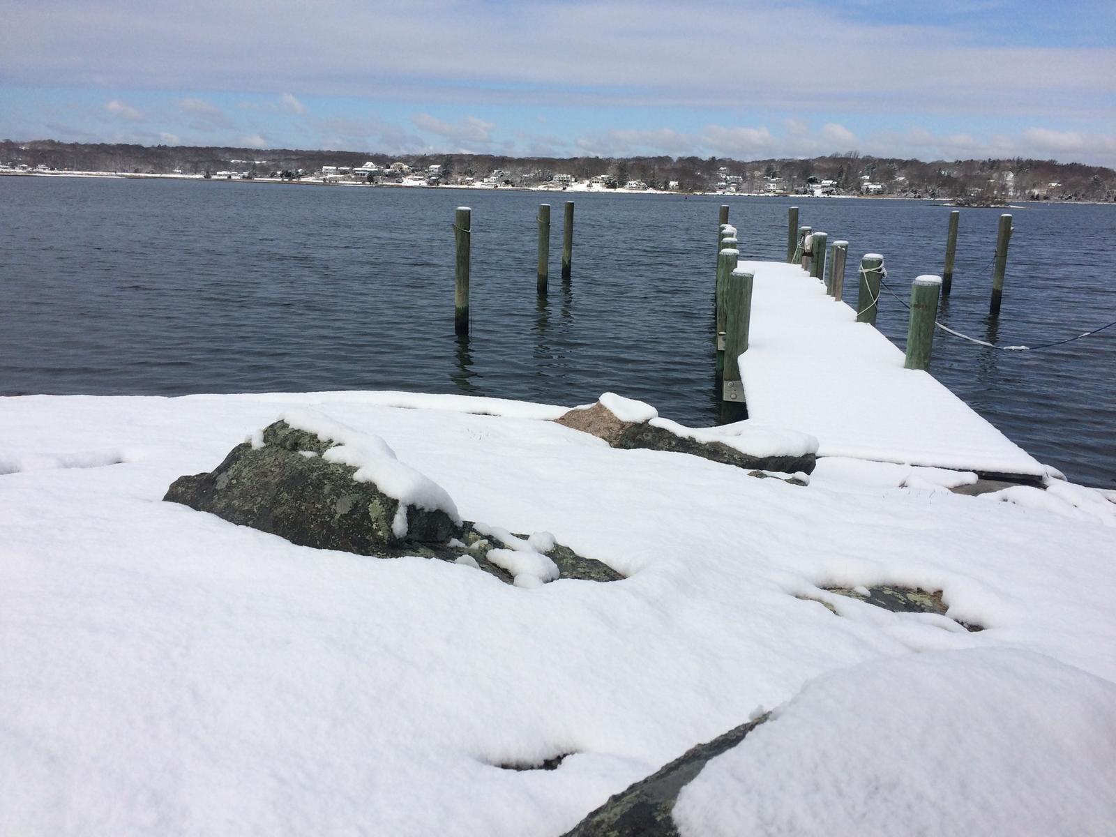 Snow-covered rocks at the point, the dock running out behind