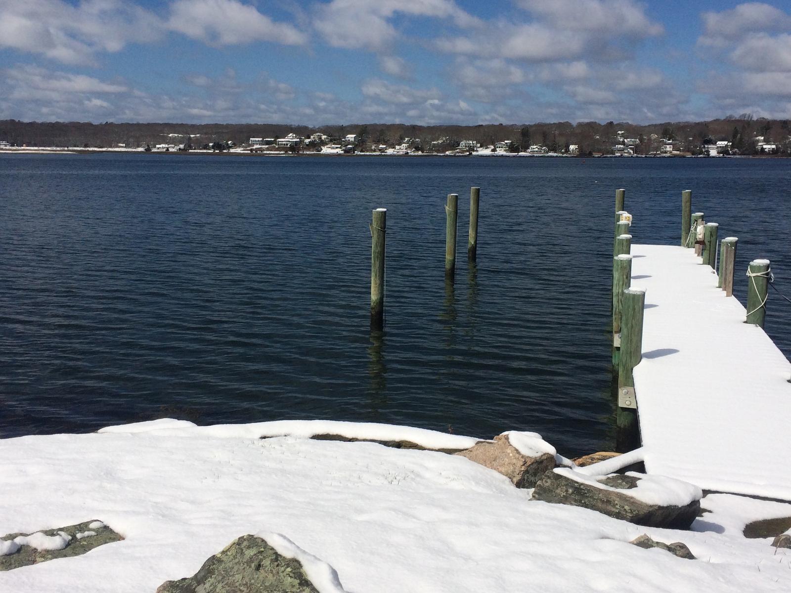 The snow-topped dock reaching into the blue on a clear day after the storm