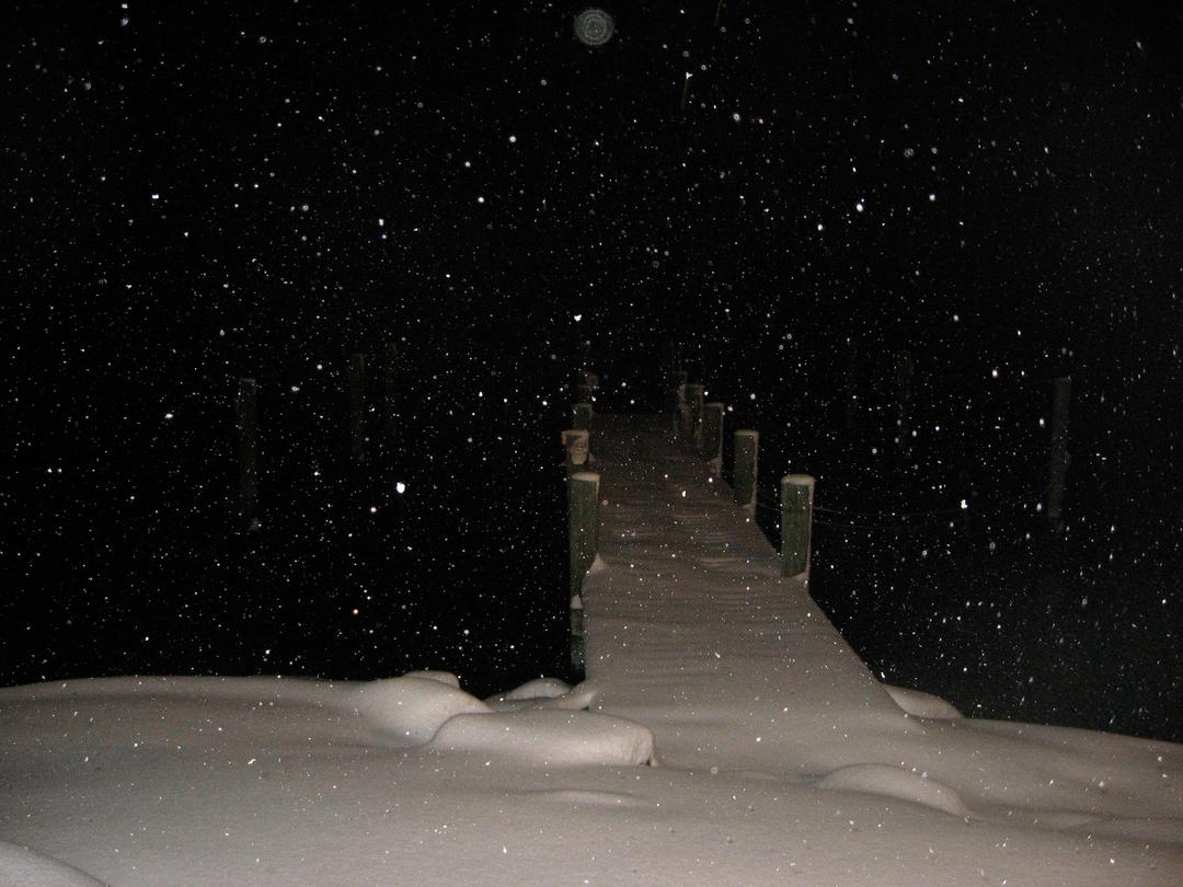Snow falling at night over the buried dock